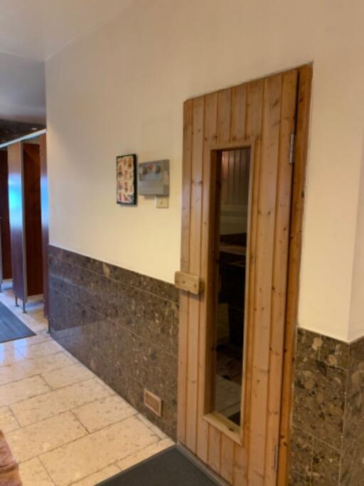 Hallway with wooden sauna door and tiled floor