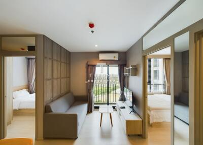 Modern living room with gray sofa, TV, and large window leading to a balcony