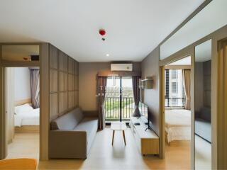 Modern living room with gray sofa, TV, and large window leading to a balcony