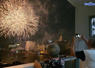 People watching fireworks from a balcony at night