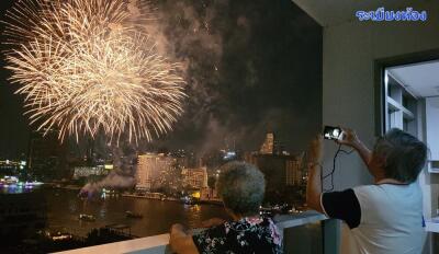 People watching fireworks from a balcony at night