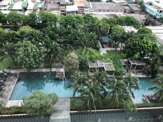 Aerial view of a swimming pool with surrounding greenery and cabanas