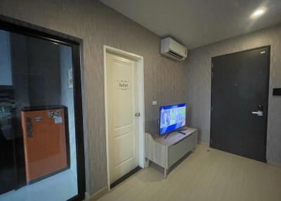 Living area with TV, air conditioning, and door to the toilet