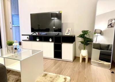 Modern living room with wooden flooring, a flat-screen TV, air conditioning, and decorative elements