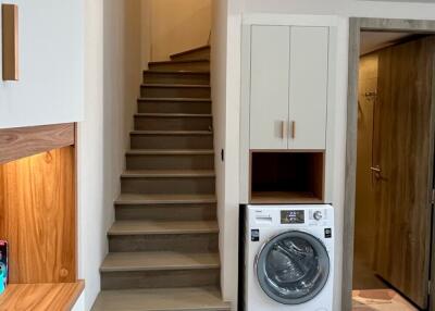 Laundry room with washing machine, stairs, storage cabinet, and door