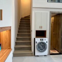 Laundry room with washing machine, stairs, storage cabinet, and door