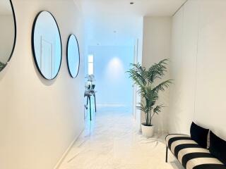 Modern hallway with mirrors, plant, and bench