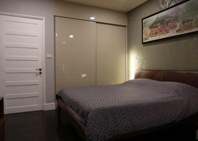 Bedroom with bed, closet, painting on wall, and closed white door