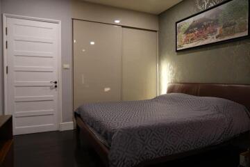 Bedroom with bed, closet, painting on wall, and closed white door