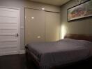 Bedroom with bed, closet, painting on wall, and closed white door