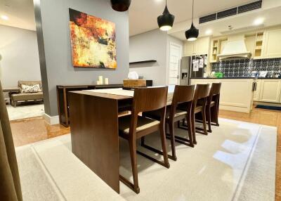 Modern dining room with wooden table and chairs, adjacent to kitchen