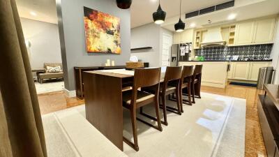 Modern dining room with wooden table and chairs, adjacent to kitchen