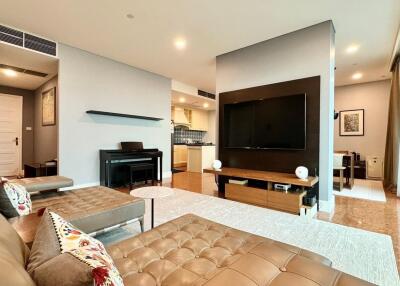 Modern living room with a sectional sofa, wall-mounted TV, and a piano