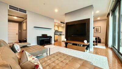 Modern living room with a sectional sofa, wall-mounted TV, and a piano