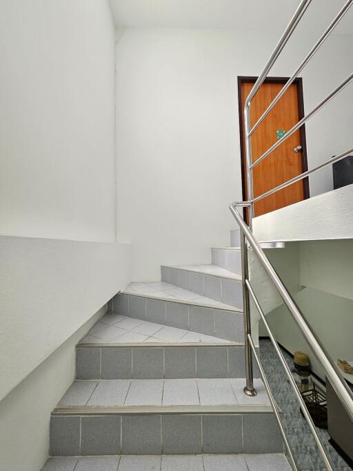 Indoor staircase with stainless steel railing and tile steps