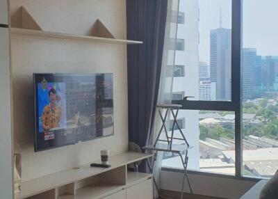 Living room with a TV, shelf, window, and city view