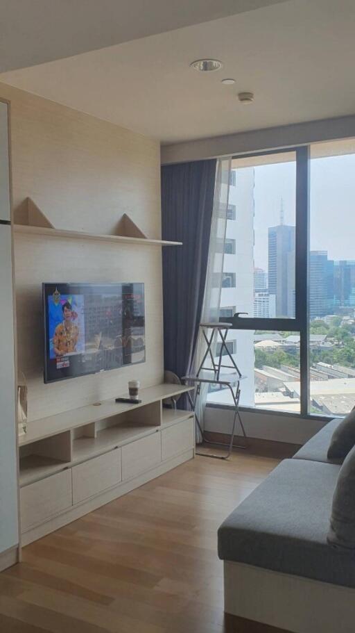 Living room with a TV, shelf, window, and city view