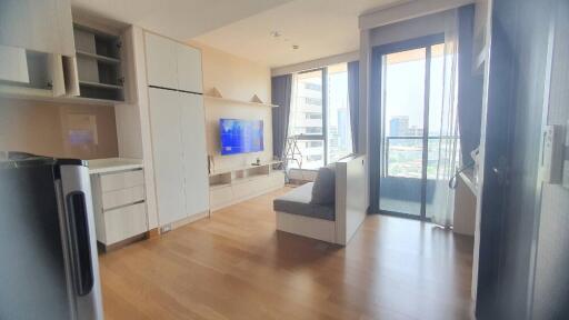 Modern living room with built-in shelves, TV, sofa, and large window with city view