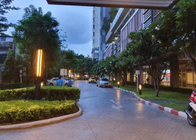 driveway and entrance to residential building with greenery and parked cars