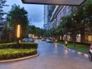 driveway and entrance to residential building with greenery and parked cars