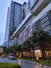 Modern apartment building exterior with shops and green landscaping