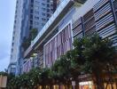 Modern apartment building exterior with shops and green landscaping