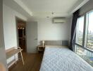 Bedroom with large windows, a bed, a small nightstand, and a city view.