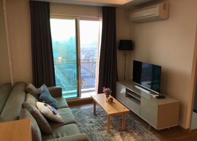 living room with sofa, coffee table, TV, and balcony