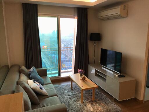 living room with sofa, coffee table, TV, and balcony