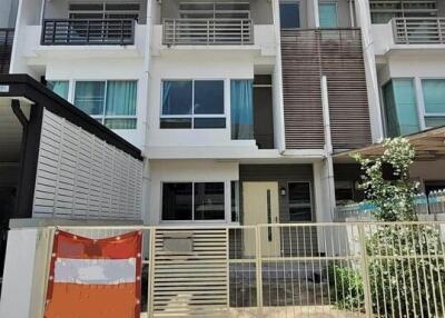 Exterior view of a modern townhouse with a gated front yard