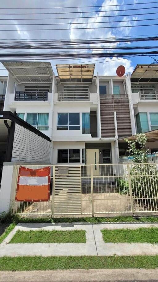 Exterior view of a modern townhouse with a gated front yard