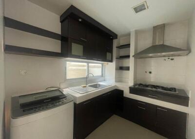 Modern kitchen with built-in cabinets, gas stove, sink, washing machine, and window