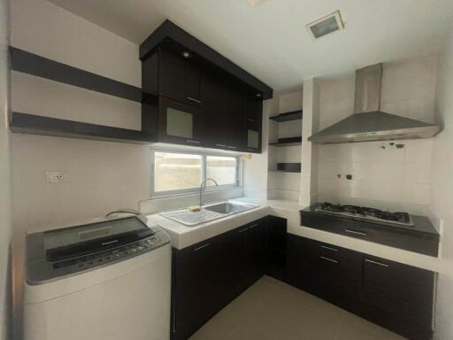 Modern kitchen with built-in cabinets, gas stove, sink, washing machine, and window