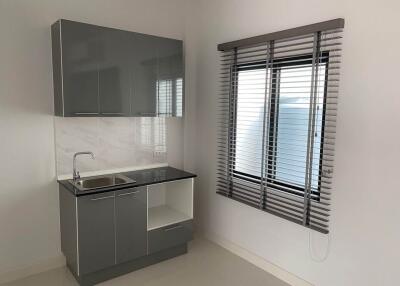 Modern minimalist kitchen with grey cabinets and window blinds