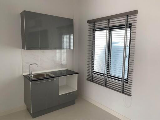 Modern minimalist kitchen with grey cabinets and window blinds