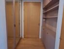 Corridor with wooden flooring, mirrored wardrobe, shelves, and wooden doors