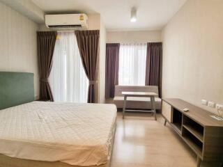 Bedroom with bed, air conditioning, large windows, and curtains