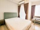 A cozy bedroom with an air conditioning unit, large bed, bedside tables, and natural light from large windows with curtains