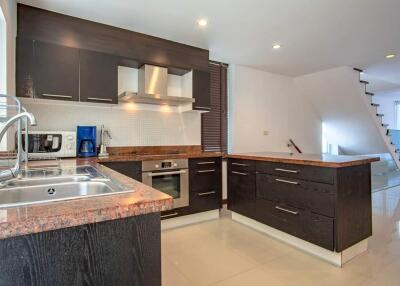 Modern kitchen with dark cabinets, stainless steel appliances, and granite countertops