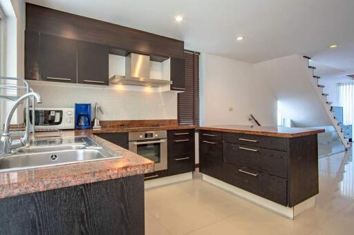 Modern kitchen with dark cabinets, stainless steel appliances, and granite countertops