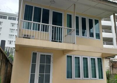 Two-story residential building with multiple windows and a small balcony