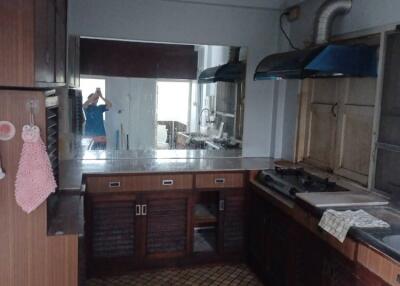 Kitchen with dark wooden cabinets, stainless steel countertop, and mirrored backsplash