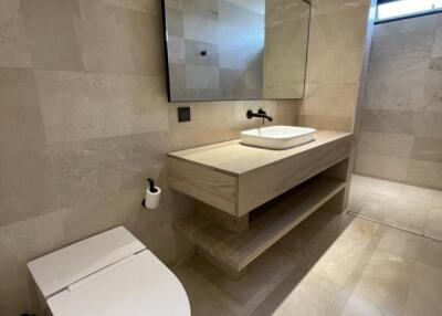 Modern bathroom with beige tiles, a large mirror, and a vessel sink