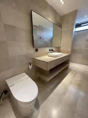 Modern bathroom with beige tiles, a large mirror, and a vessel sink