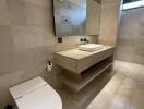 Modern bathroom with beige tiles, a large mirror, and a vessel sink