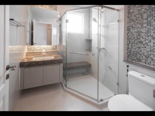 Modern bathroom with glass shower, vanity with sink, mirror, and toilet