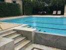 Swimming pool area with steps and lounge chairs