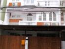 Three-story white building with balconies and wooden gate