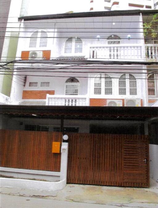 Three-story white building with balconies and wooden gate