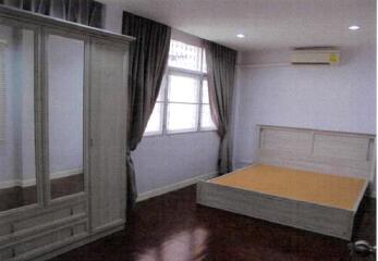 A well-lit bedroom with a large wardrobe and bed frame